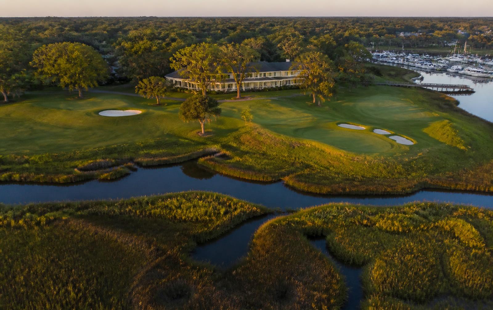 Aerial view of a South Carolina Lowcountry golf club beside tidal marsh creeks near Hilton Head at golden hour.