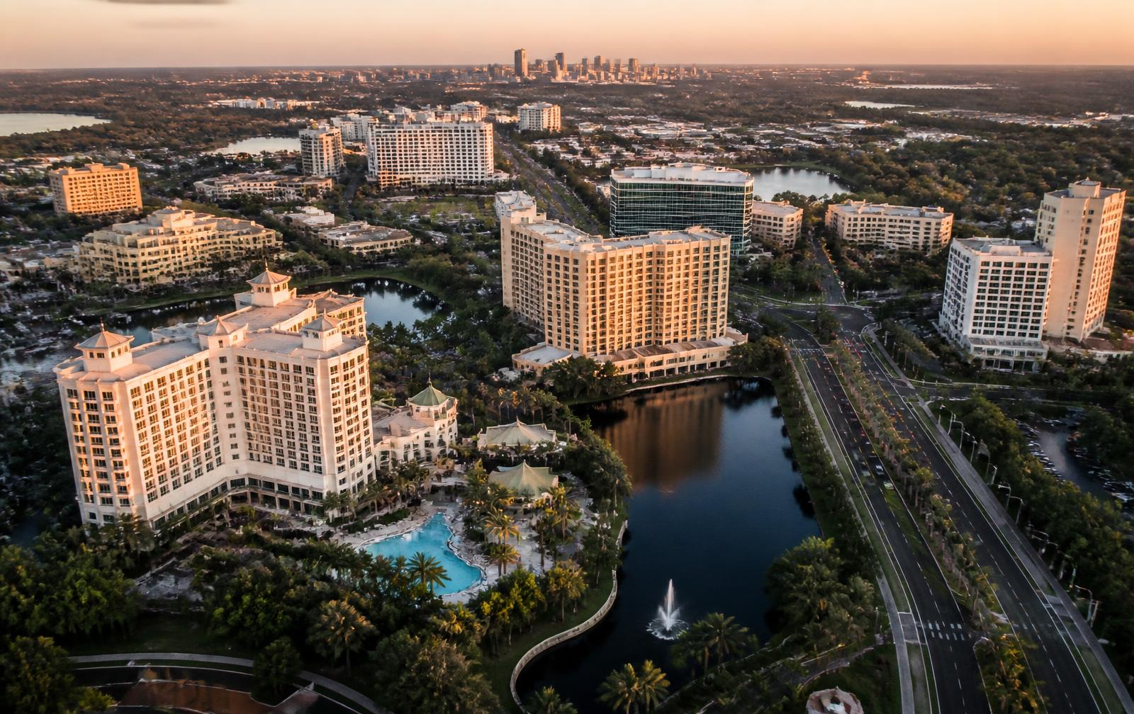 Aerial view of the Orlando, Florida resort hotel corridor at golden hour with the downtown skyline in the distance.